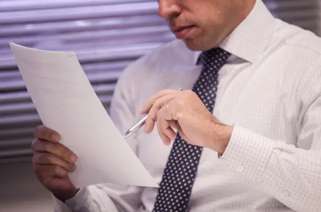 Executivo analisando documentos em ambiente corporativo